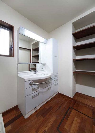 浴室外的梳妆间，白色的洗手台组合，显得干净整洁旁边利用空隙搭建层架，可以放置换洗的毛巾和衣物，十分方便